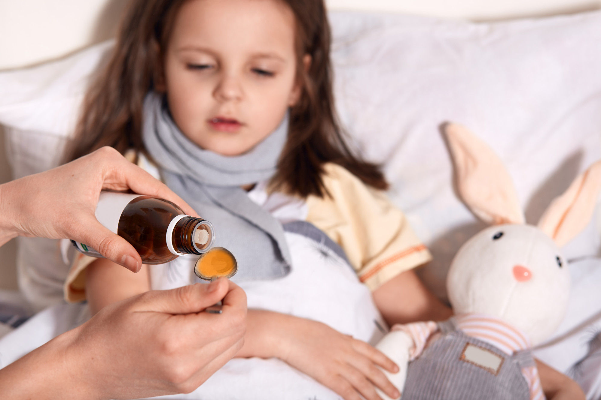 horizontal-photo-unknown-hand-pouring-liquid-into-spoon-from-little-bottle-with-syrup-person-caring-about-child-lying-bed-with-flu_176532-9505